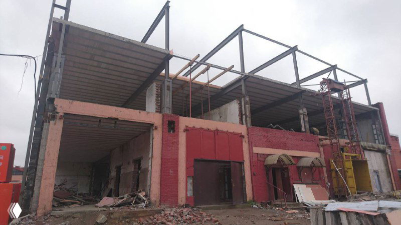 Фасад и каркас здания в процессе надстройки: видны металлические элементы для формирования новых этажей и начальные работы по внешней обшивке.