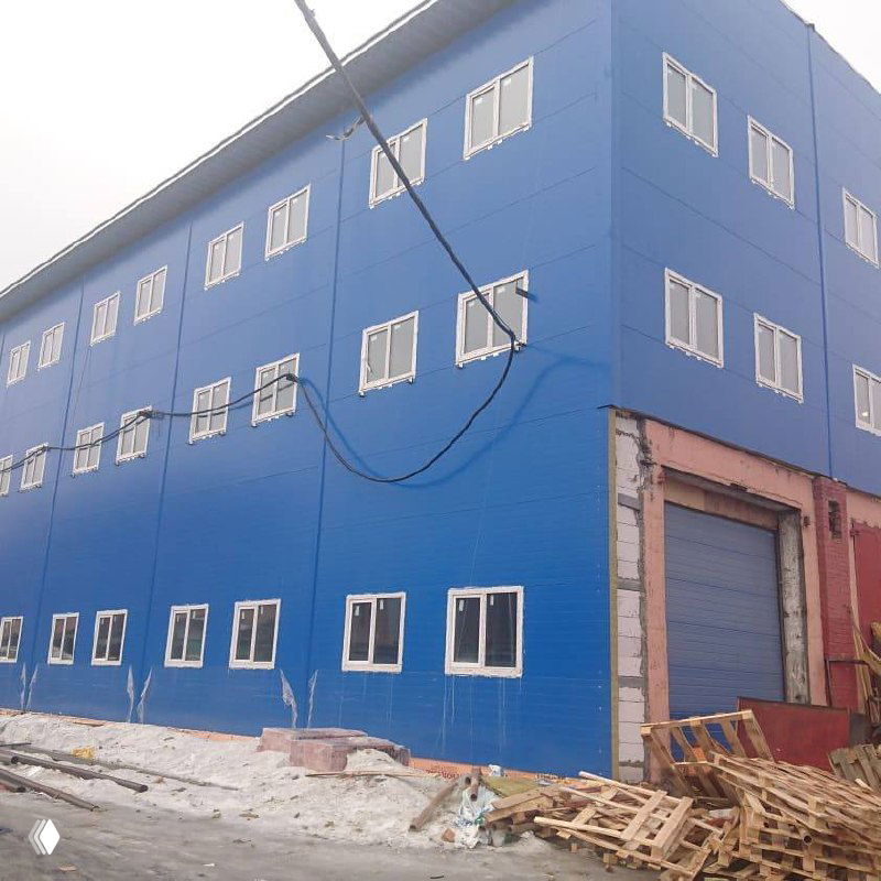 Готовая синяя облицовка фасада нового трёхэтажного корпуса, окна и промышленные ворота в окончательной компоновке — внешний вид после реконструкции.