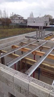 Вид сверху на монтаж межэтажного перекрытия: металлические балки МАРКО, подпорки и блоки из керамзитобетона на строительной площадке.