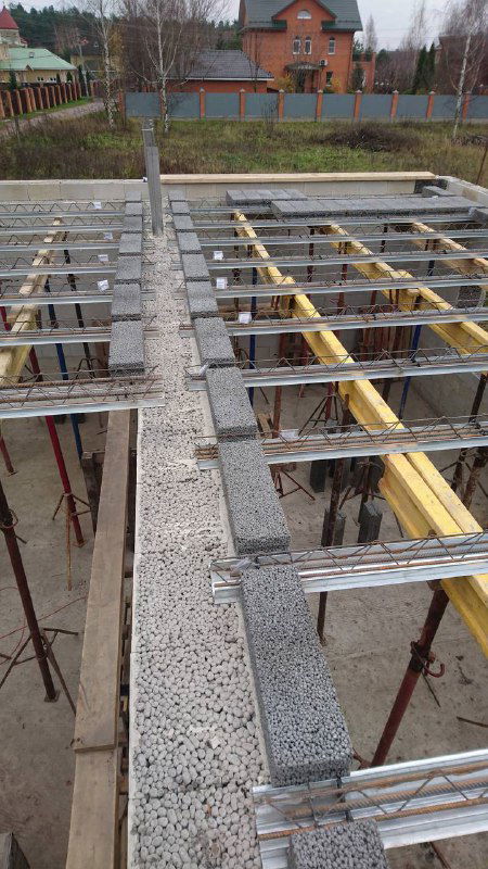 Монтажное состояние перекрытия: балки, подпорки и блоки на переднем плане; на заднем плане — ограждение участка и соседние дома.