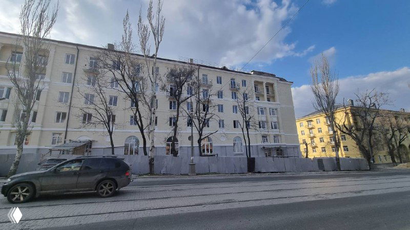 Широкий вид восстановленных домов вдоль улицы: фасады окрашены, приведены в порядок тротуары и ограждения, городская улица после работ по реконструкции.