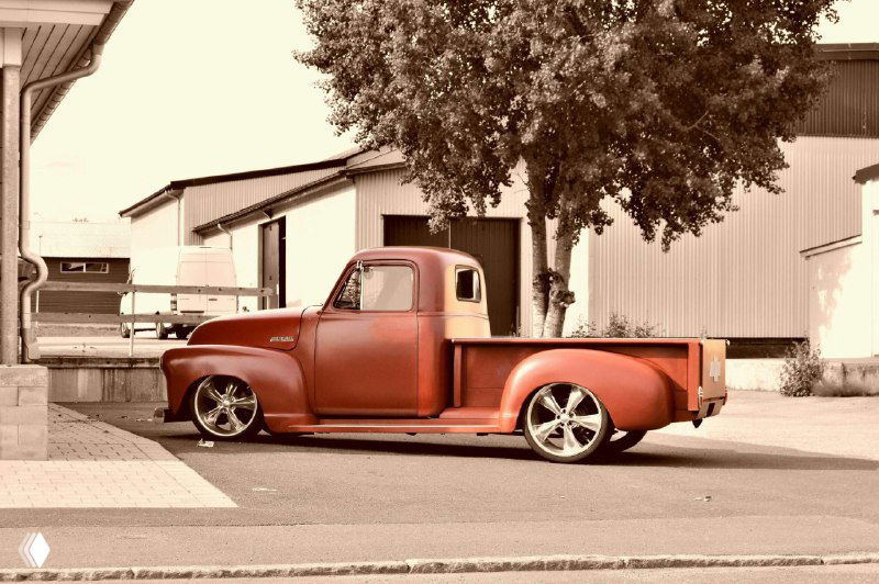 Ретро-пикап на парковке в тёплой тонировке, низкий ракурс и подчёркнутые линии кузова создают эстетическую атмосферу ностальгии.