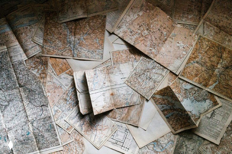 Разложенные старые карты и листы — визуальная метафора поиска пути в карьере, навигации по возможностям и стратегическому выбору.