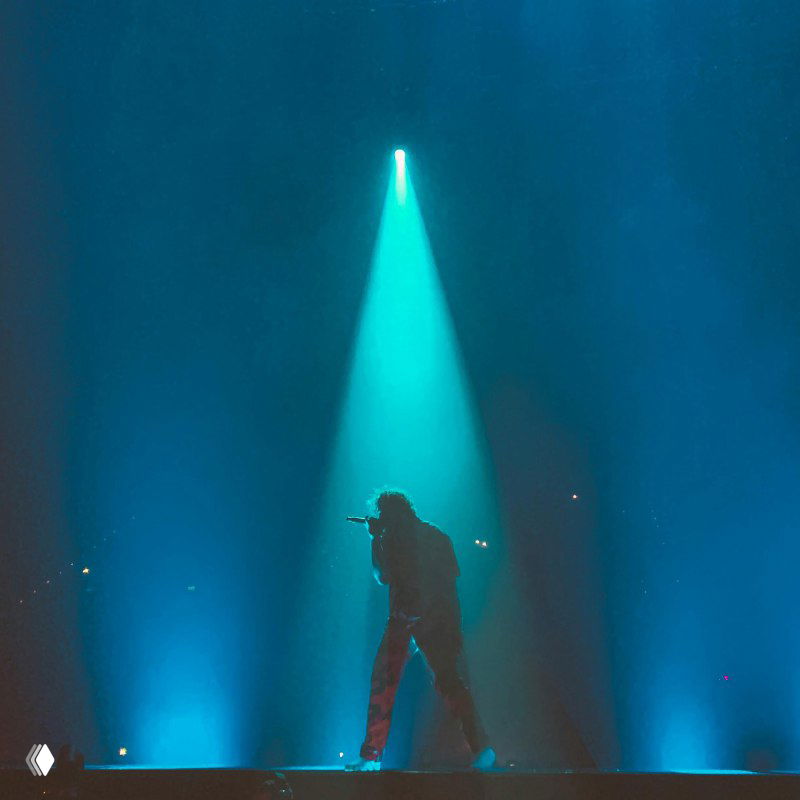 Артист под синим прожектором на большой сцене, силуэт исполнителя и направленный свет — образ публичной видимости, выступления и демонстрации экспертизы.