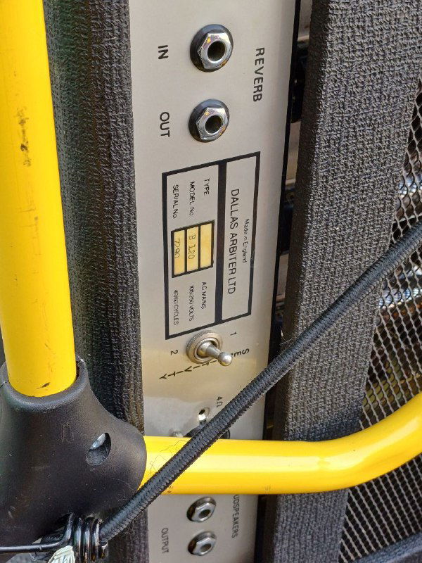 Крупный план боковой панели усилителя Sound City: разъёмы, переключатели и яркая жёлтая защитная рама с видимыми креплениями и текстурами корпуса усилителя.