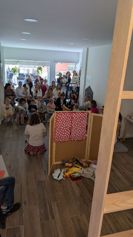 Вид на входной зал центра: большое скопление родителей и детей у входа, видна игровая зона, полки и элементы доступной среды Монтессори.