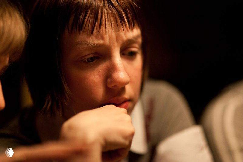 Крупный план человека в раздумье, лицо вблизи, мягкое тёплое освещение, интимный портрет, отражение эмоций и внутренней борьбы.