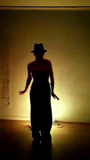 Силуэт танцовщицы в шляпе на тёплом подсвеченном фоне в помещении, атмосферное фото для анонса занятий и марафона по практике Ятанец.