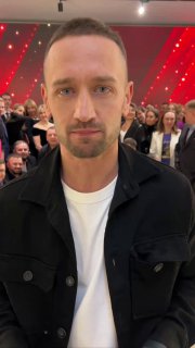 Портрет мужчины на фоне красной сцены и публики в зале — репортажный кадр с деловой церемонии и награждения «Итоги 2024 UDS».