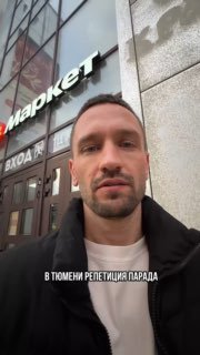 Селфи автора на фоне входа в здание с вывеской; мужчина смотрит в камеру, на фото видна подпись «В ТЮМЕНИ РЕПЕТИЦИЯ ПАРАДА», городской контекст.