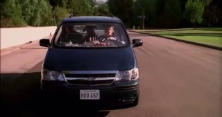 Машина едет по пригородной улице — сценический кадр из сериала, иллюстрирующий бытовую рутину и семейный контекст персонажей.