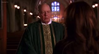 Священник в церковном одеянии обращается к женщине в храме — кадр из сериала, подчёркивающий моральные и религиозные мотивы в сюжете.