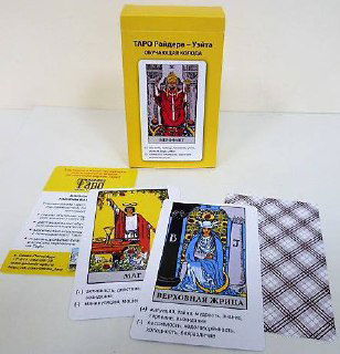 Жёлтая коробка колоды Райдера-Уэйта на белом фоне с открытыми картами и инструкцией — комплект для демонстрации карт.