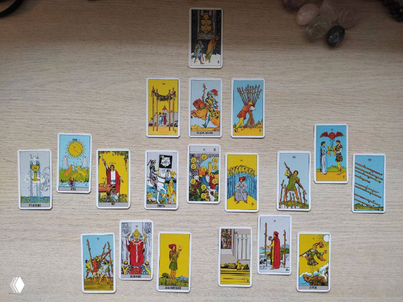 Фотография реального расклада Таро: разложенные на столе карты, видно масти и центральные позиции на светлой деревянной поверхности.
