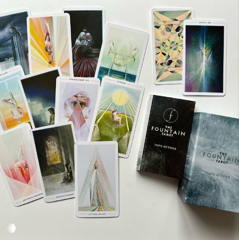 Разложенные карты современной колоды с мягкой палитрой и абстрактными иллюстрациями рядом с двумя коробками колоды на светлом фоне.