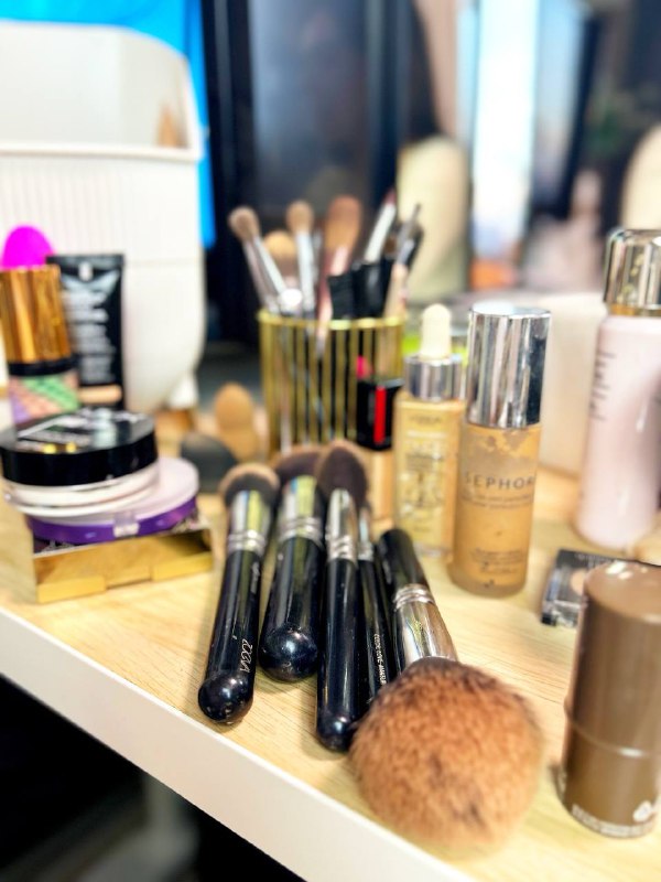 Рабочий стол визажиста: набор кистей, тональные средства, палетки и баночки аккуратно разложены на столе, готовность к уроку и демонстрации техник.