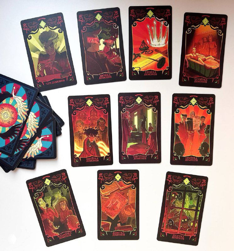 Фото раскладываемых карт таро в тёплой красной гамме: карты масти Демонов и другие арканы, часть стопки лежит в веере.
