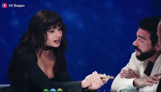 Кадр студийного шоу: женщина демонстрирует карты мужчине за столом, обсуждается тасовка колоды и техника работы с Таро.