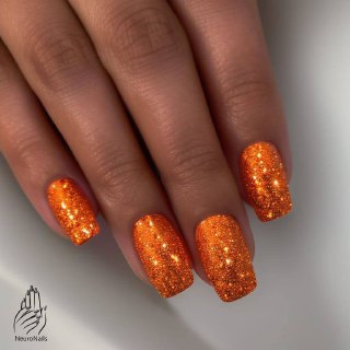 Блестящие оранжевые ногти с глиттерным покрытием на естественной длине, текстура мерцает на свету и создаёт эффект свечения.