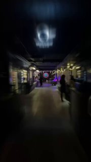 Размытый коридор и пространство клуба с движением людей вдалеке, тусклое освещение и проекция на потолке — динамичный кадр с события, где проходили расклады.