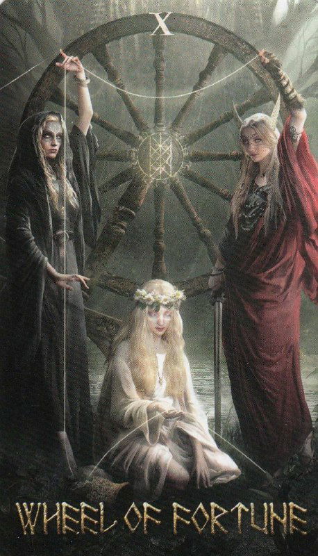 Темная мистическая карта с тремя фигурами вокруг большого колеса: ритуальная атмосфера, символы судьбы и коллективного влияния на жизнь.