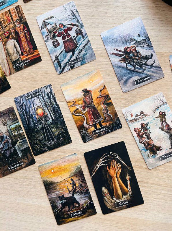 Набор карт Таро с доминированием холодных тонов: зимние пейзажи, фигурки персонажей и символика, создающая атмосферу.