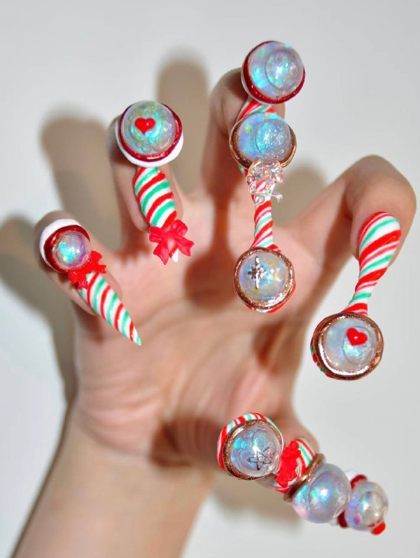 Фантазийный маникюр в стиле леденцов: красно‑белые спирали, бусины и прозрачные сферические элементы, игривый праздничный декор на ногтях.