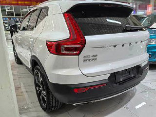 Белый Volvo XC40, вид сзади в выставочном зале; видна крышка багажника и шильдики модели, демонстрация состояния кузова и отсутствия номеров.