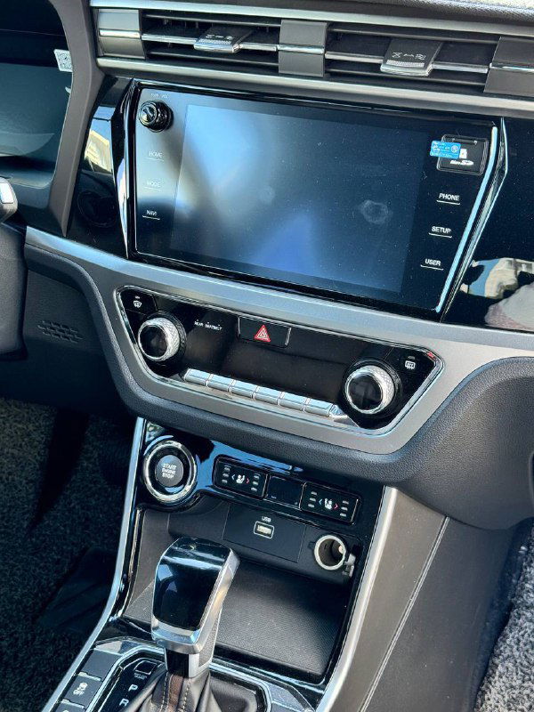 Центральная консоль с крупным экраном мультимедиа, кнопками климата и декоративной панелью — вид на мультимедийную систему автомобиля