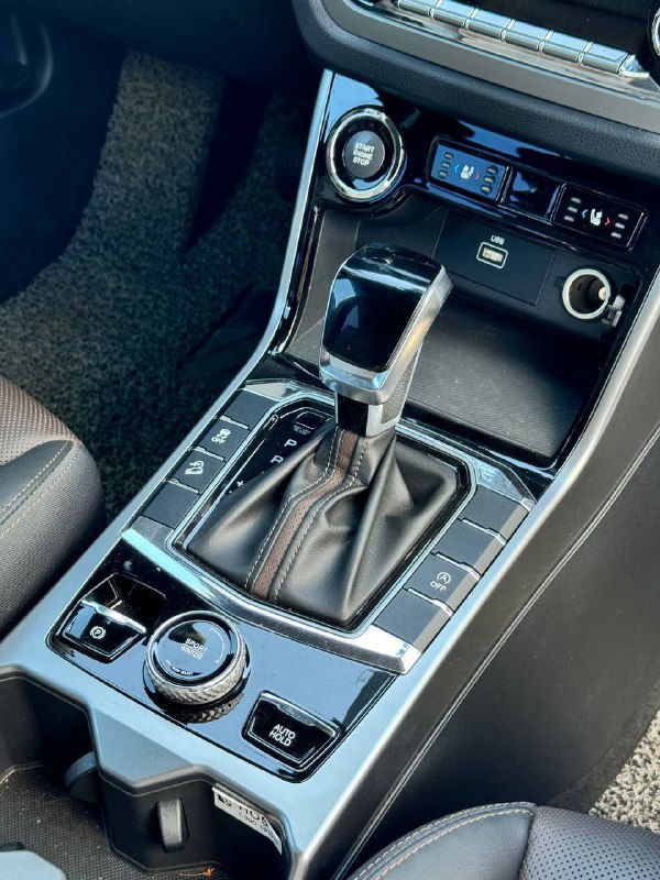 Рычаг автоматической коробки передач и панель управления на центральной консоли SsangYong Korando, видны селектор, кнопки и элементы отделки вокруг