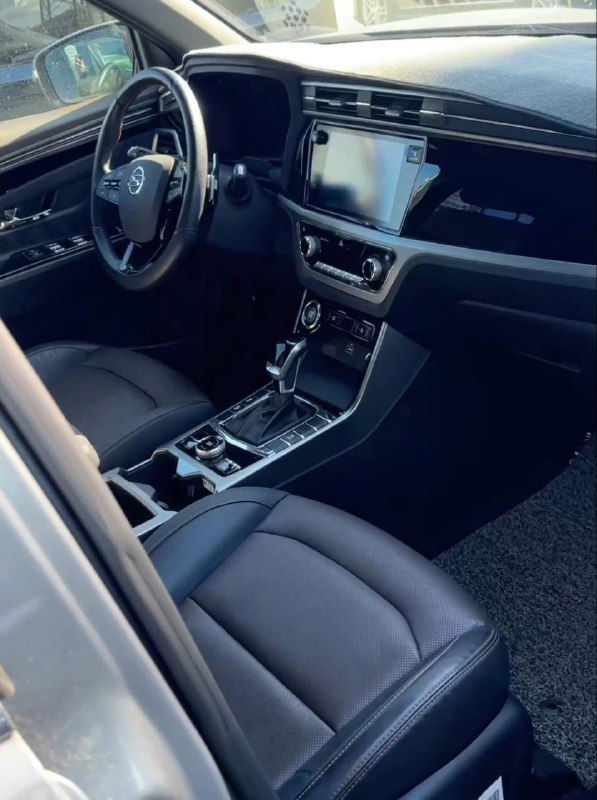 Широкий ракурс салона с рулём, передними сиденьями и центральной консолью SsangYong, видна общая эргономика и материалы отделки