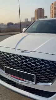 Крупный план передней декоративной решётки и капота белого автомобиля Genesis GV80; кадр из отчёта о подготовке к отправке клиента.