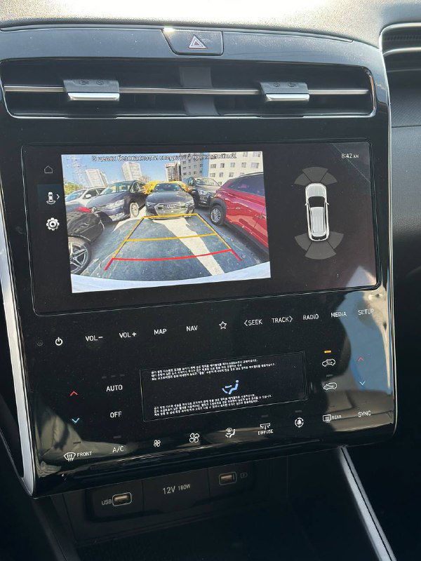 Монитор медиасистемы Hyundai Tucson с изображением камеры заднего вида на экране и интерфейсом панели управления, демонстрирующий работу системы парковки и камеры.