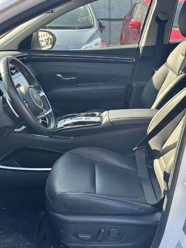 Вид внутри салона Hyundai Tucson с открытой дверью: пассажирское сиденье, центральный подлокотник и пространство в салоне, показывающие компоновку и комфорт для покупателя.