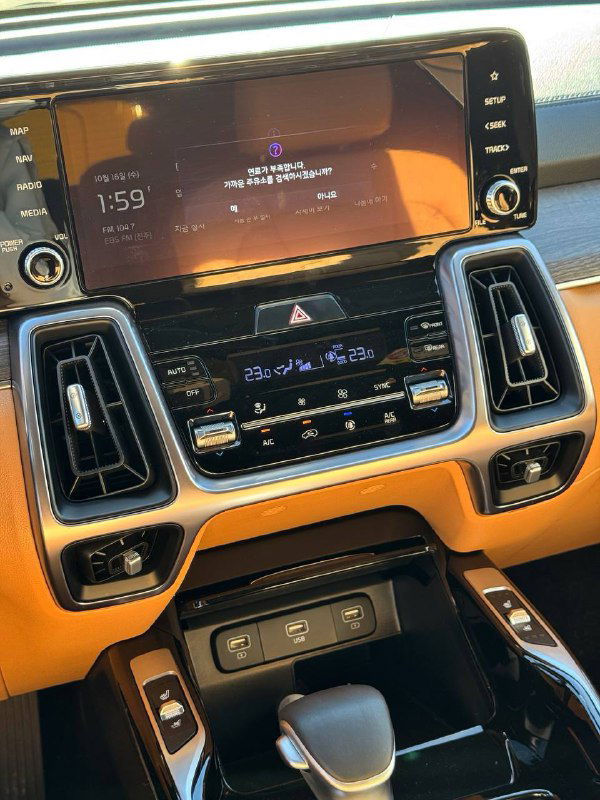 Фотография центральной консоли и мультимедийного экрана KIA Sorento, видно климат-контроль, декоративные вставки и кнопки управления.