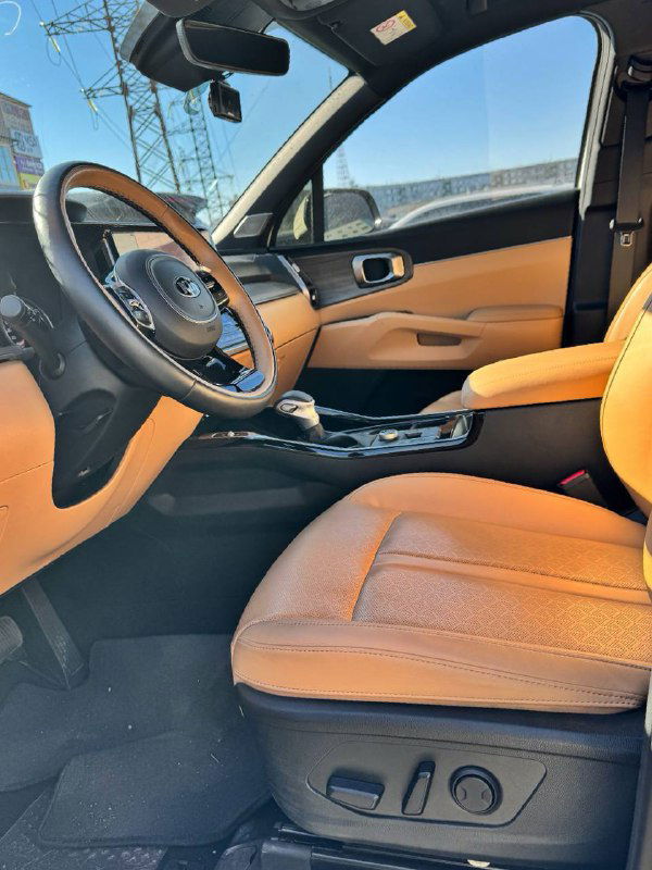 Выгляд сиденья водителя и переднего пассажира KIA Sorento — коричнево-бежевые кожаные сиденья с электроприводом и декоративной прострочкой.
