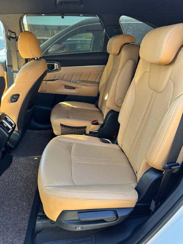 Фотография второго ряда сидений KIA Sorento с бежевой кожаной обивкой, вид на пространство для ног и комфортные подголовники.