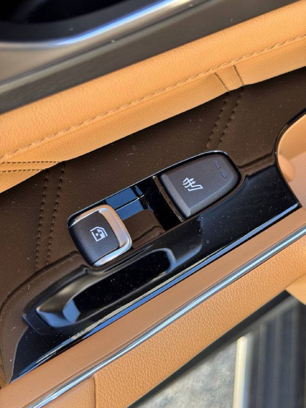 Крупный план кнопок и оконного переключателя на дверной панели KIA Sorento с коричнево-бежевой отделкой и декоративной прострочкой.