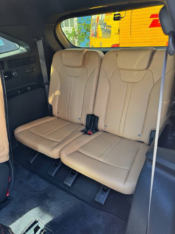 Фото третьего ряда или заднего пространства салона KIA Sorento с бежевой обивкой сидений, вид на складные сиденья и ремни безопасности.