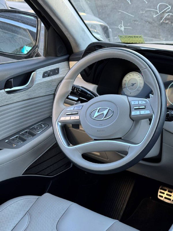 Крупный план руля и передней части салона Hyundai Palisade: светлая отделка сидений, рукоятки управления и элементы панели водителя в кадре.