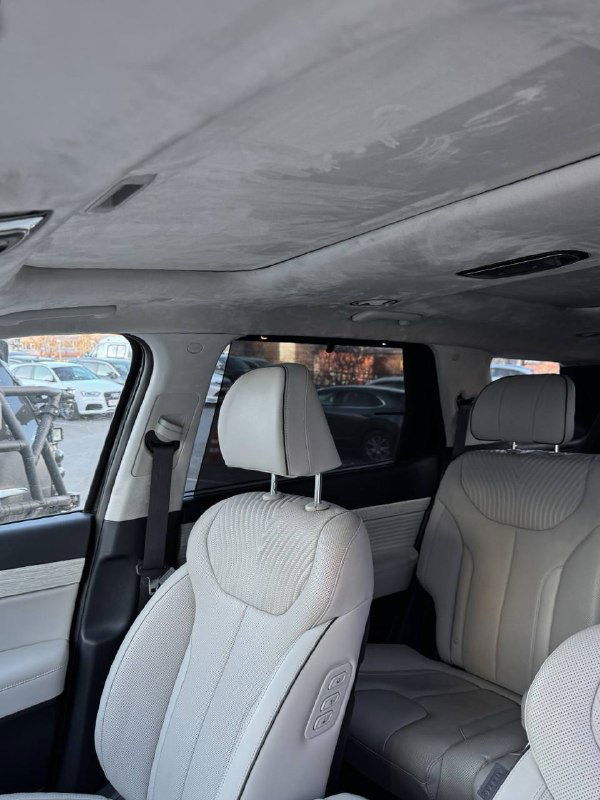 Общий вид салона Hyundai Palisade сверху: потолок, второй ряд и часть третьего, светлая обшивка и общий объём внутреннего пространства автомобиля.