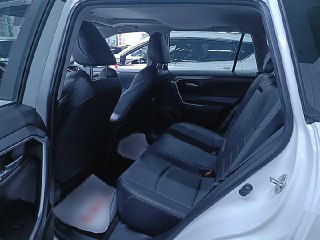 Задние пассажирские сиденья Toyota Wildlander 2020 в белом кузове — чёрная тканевая обивка, пространство ног и общий вид второго ряда салона через открытую дверь.