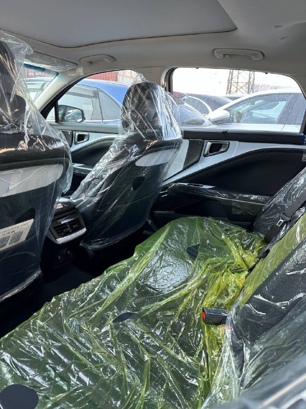 Вид на задние сиденья KIA K8 2024 с защитными плёнками: пространство для пассажиров, обшивка и состояние салона после транспортування или поставки.