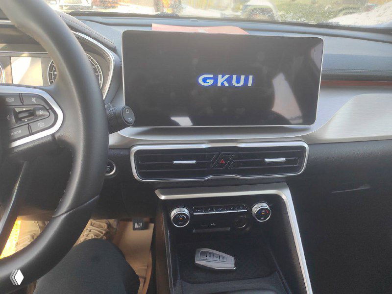 Салон Geely Coolray: крупный план центральной мультимедийной панели с надписью GKUI, руль и блок климат‑контроля для ознакомления с оснащением.