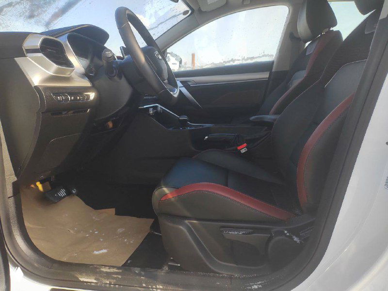 Переднее сиденье и пространство салона Geely Coolray с чёрной отделкой и красной прострочкой, видно состояние обивки, поручней и пола возле двери.