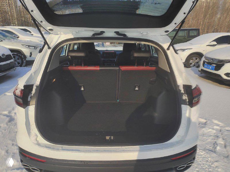 Открытый багажник Geely Coolray 2021: вид на грузовое пространство, задние сиденья сложены частично, видно состояние пола и уплотнителей.