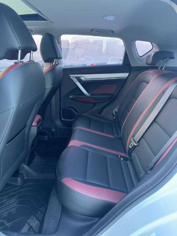 Задние сиденья Geely Coolray 2021 в чёрно-красной обивке, пространство для ног и состояние салона видно на фоне внешней зимней стоянки.