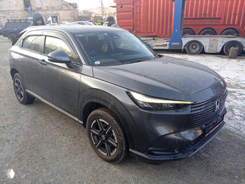 Honda Vezel 2021 — боковой вид на открытой площадке у контейнера и автовоза; видны колёса, состояние кузова и подготовка к отправке.