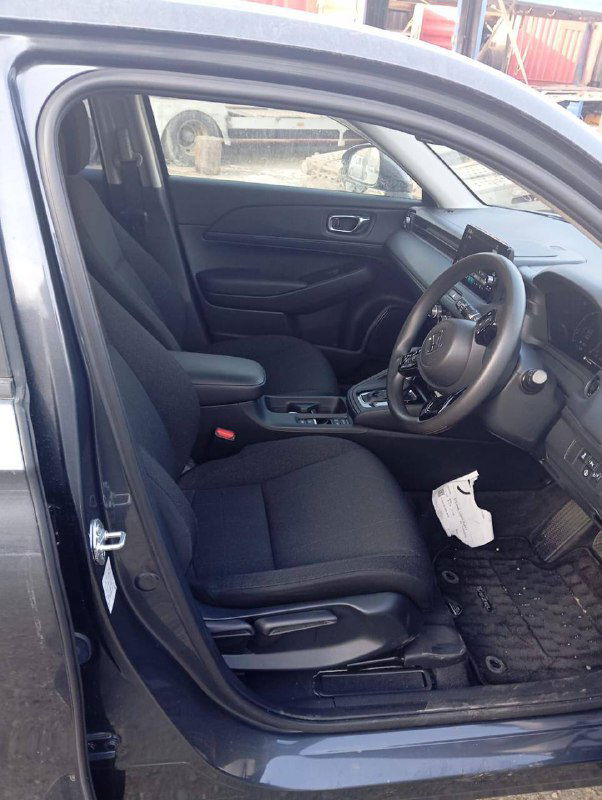 Интерьер Honda Vezel 2021 — переднее сиденье, руль и центральная консоль; чёрная ткань, салон показан в рабочем состоянии перед отправкой.