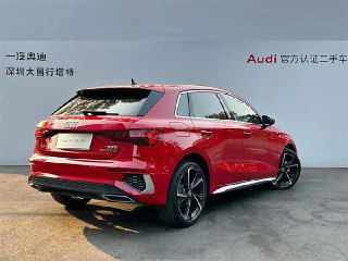 Красный Audi A3 2022 вид сзади-право — видны задний бампер, фары и профиль хэтчбека на фоне стенда